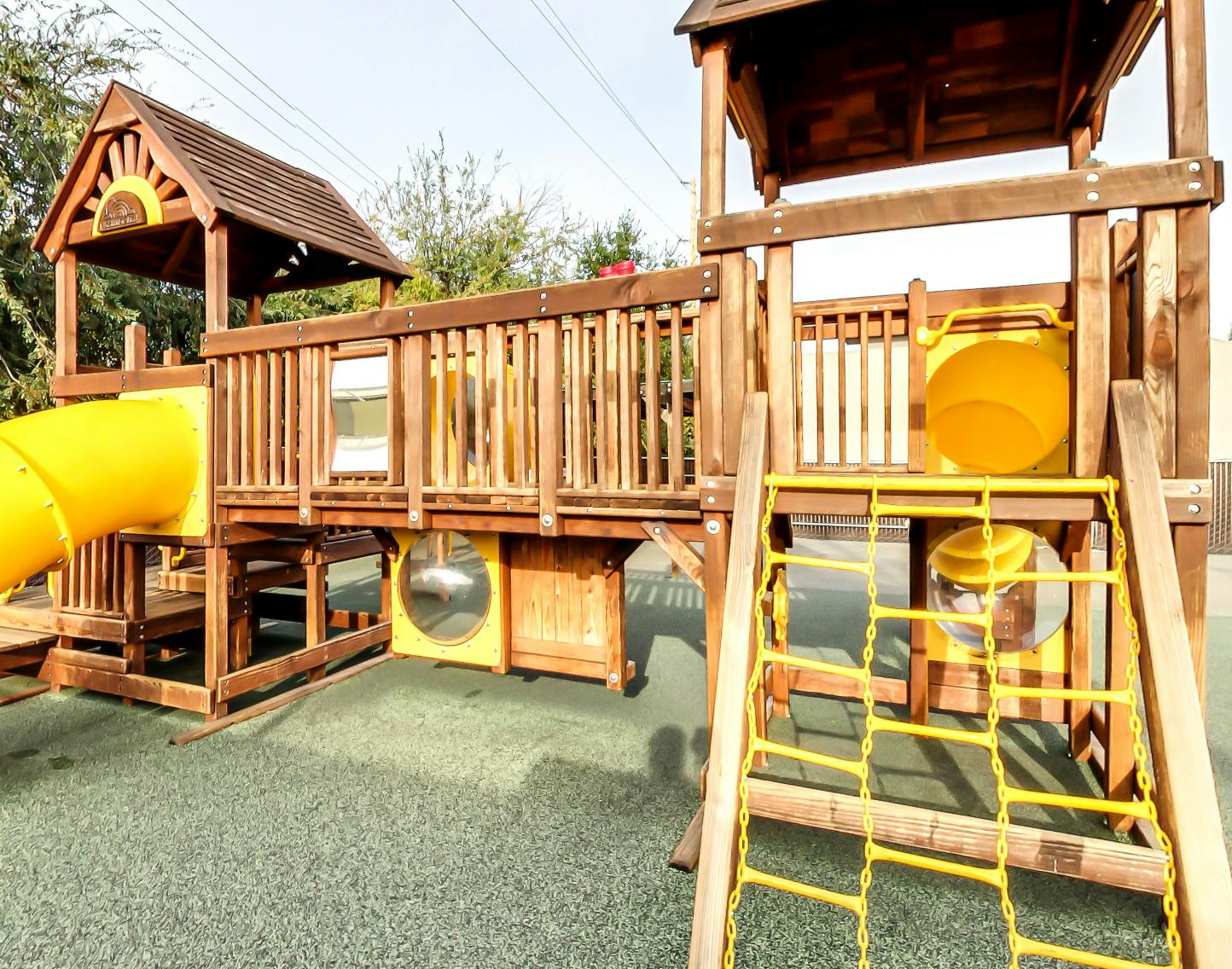 Wooden playground structure with yellow slide and climbing net