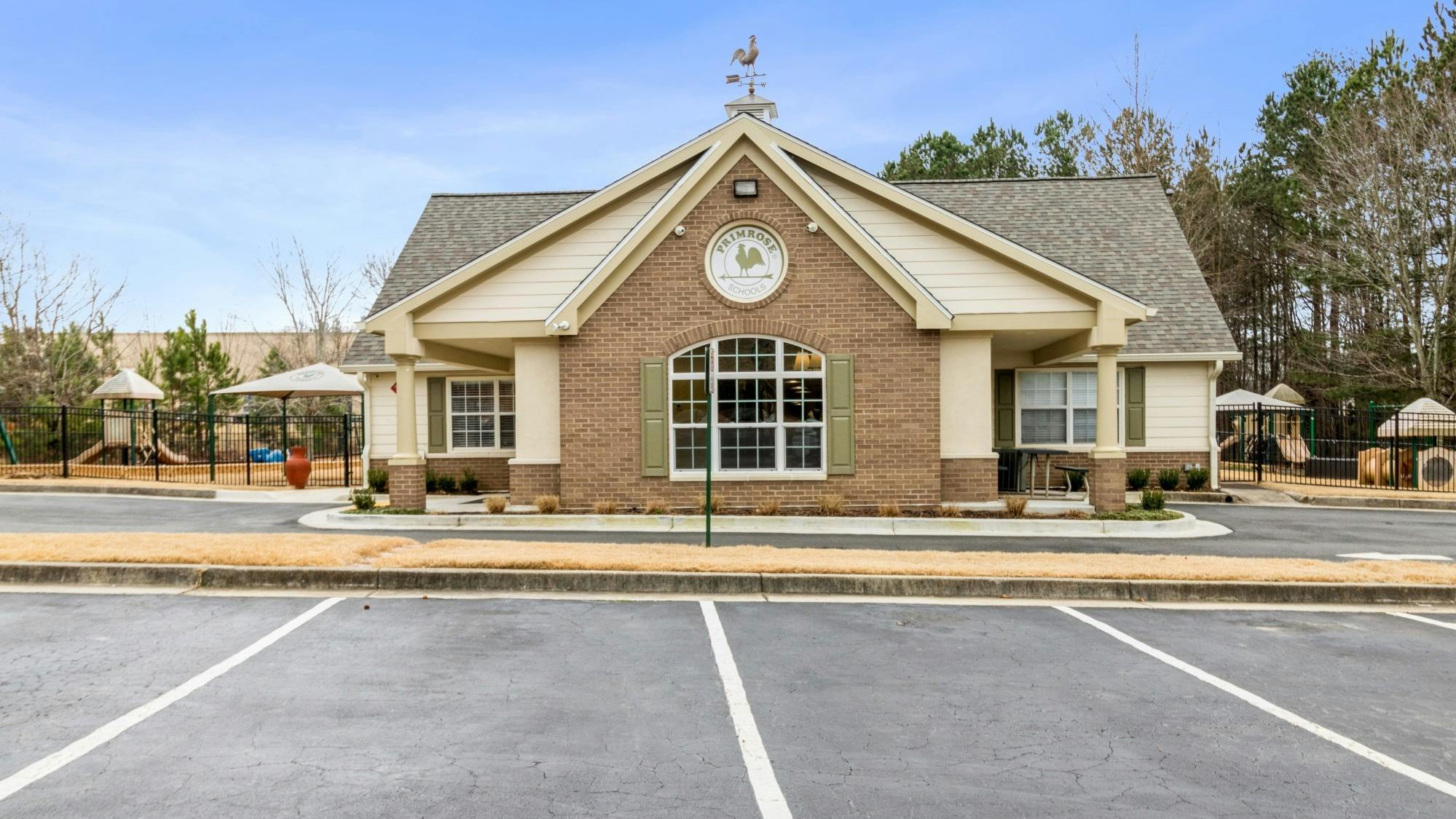 Building with brick facade and large arched window, parking lot in foreground