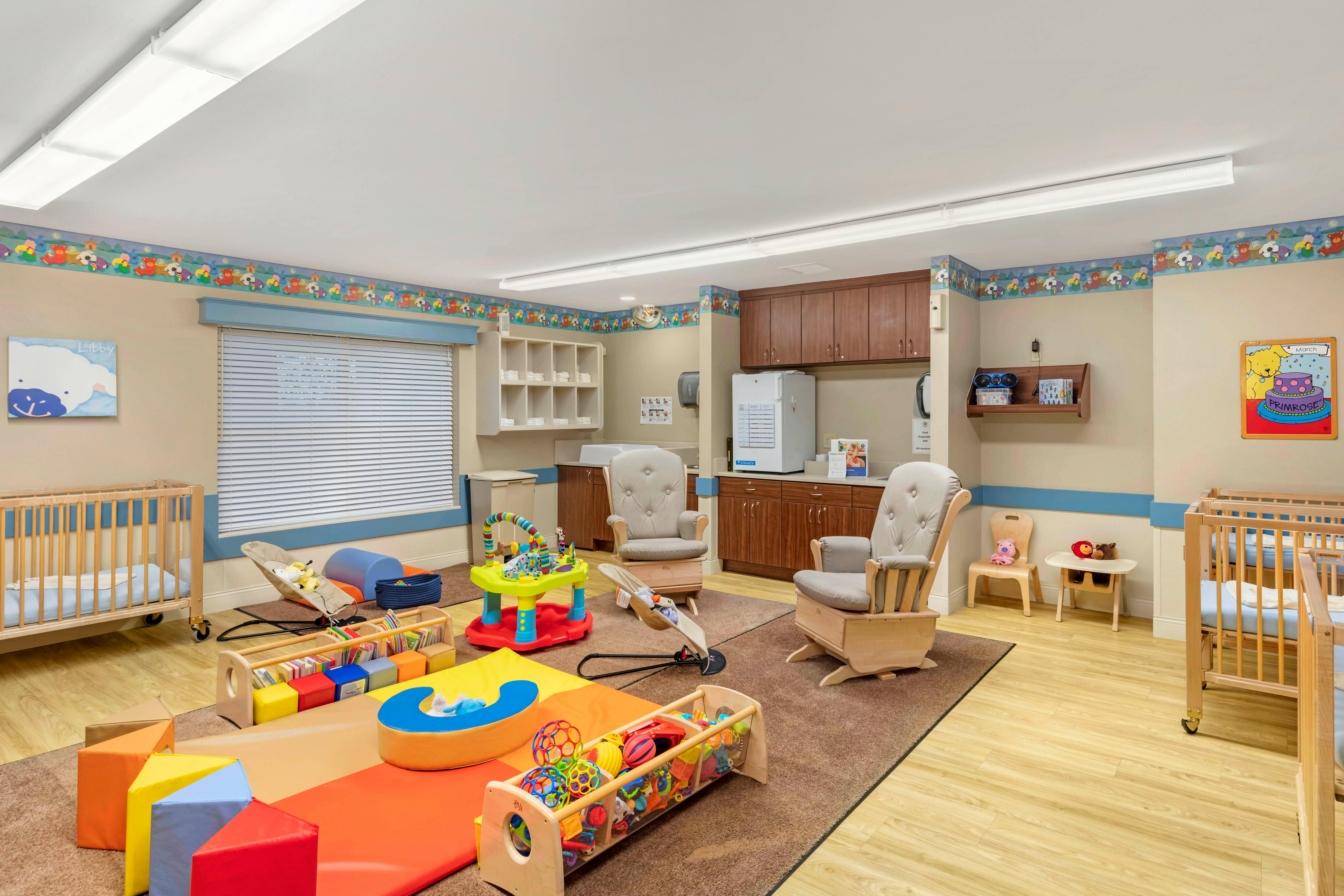 A colorful playroom or nursery with multiple cribs, rocking chairs, and toys
