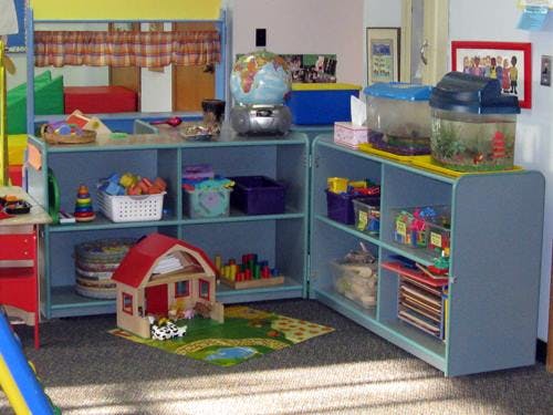 Classroom with shelves of toys, a dollhouse, and fish tanks