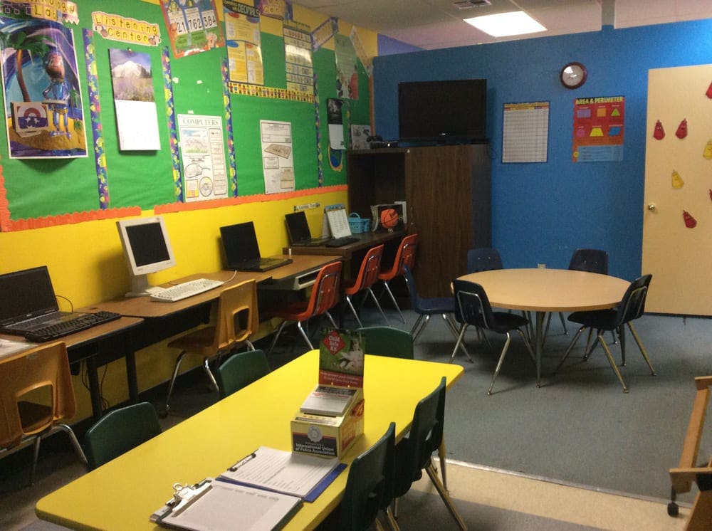 Classroom with computers on desks and a round table with chairs