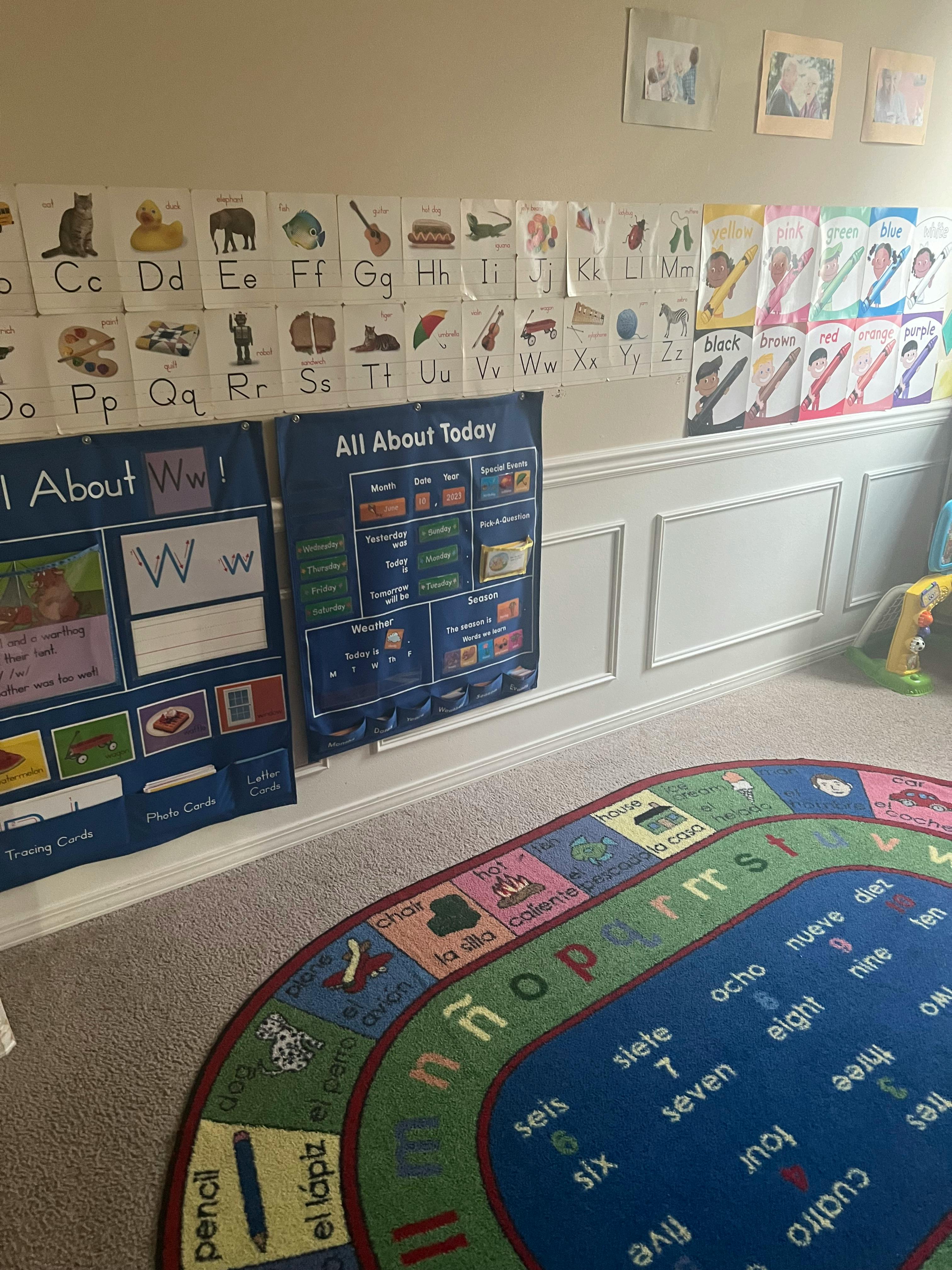 Classroom wall with alphabet charts and a colorful rug with letters and numbers