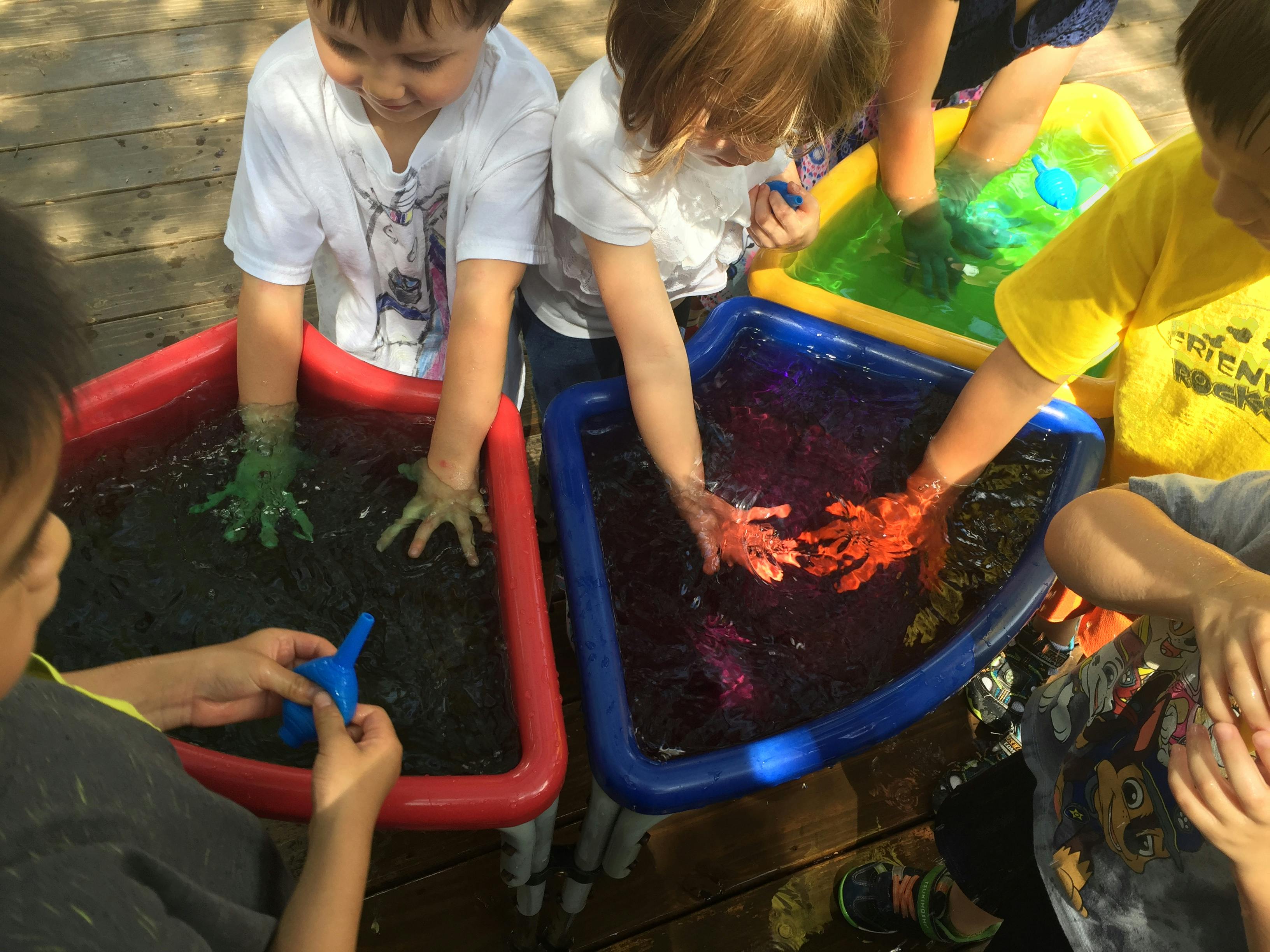 Children playing with colorful water in sensory bins