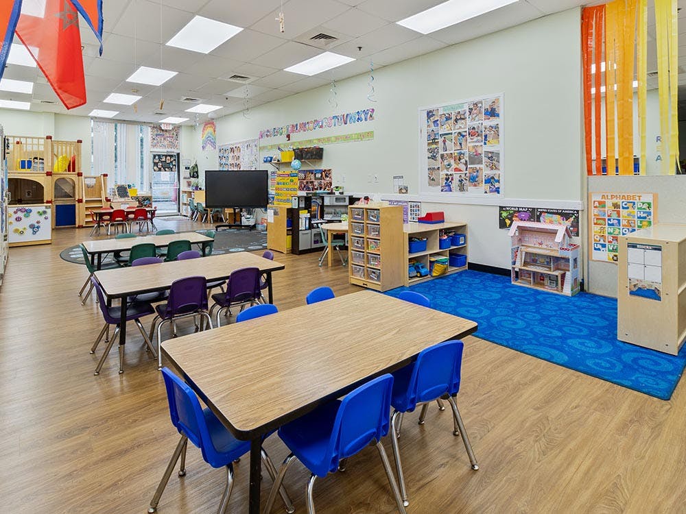 A colorful empty classroom with tables and chairs for young children