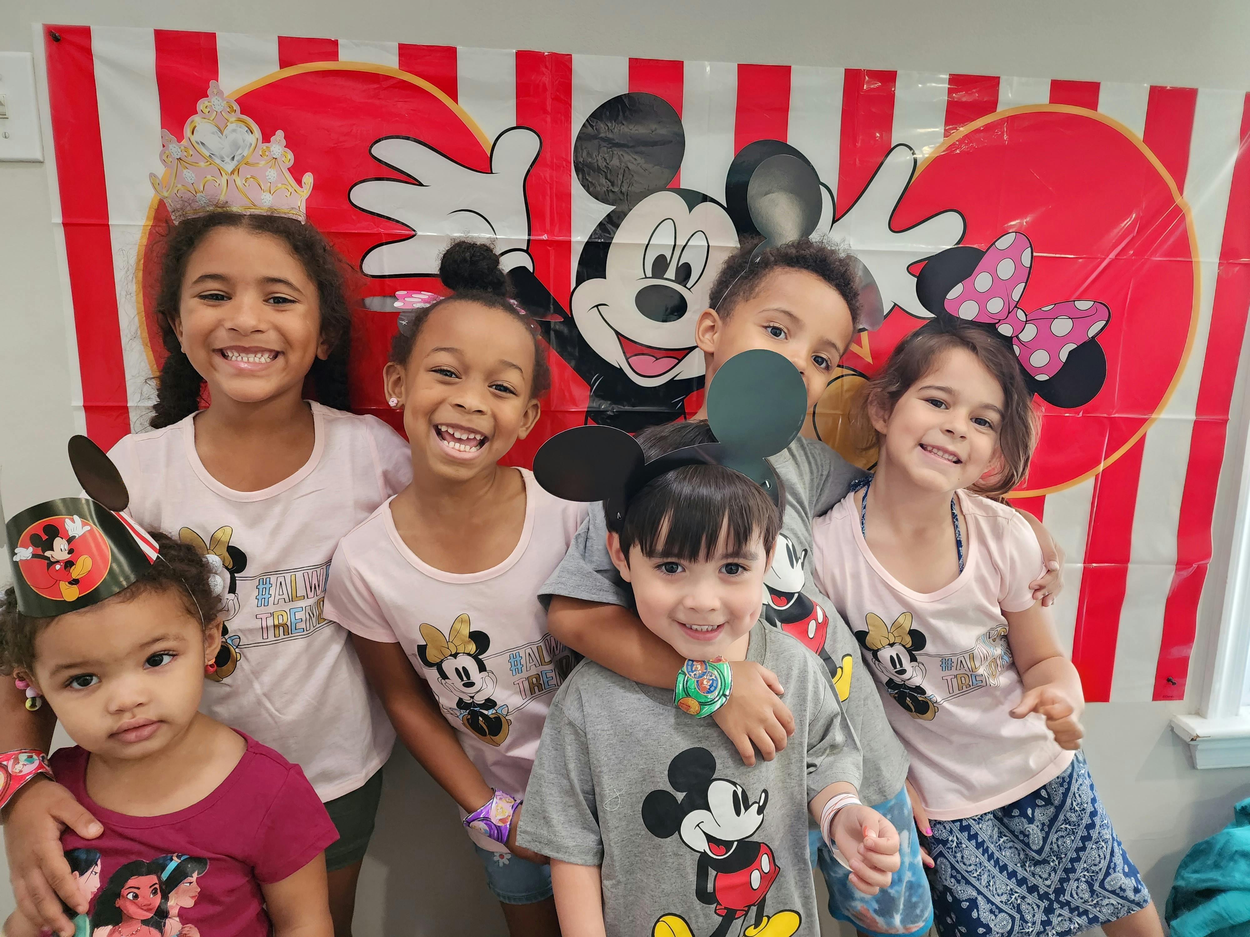 Group of children posing in front of a Mickey Mouse banner