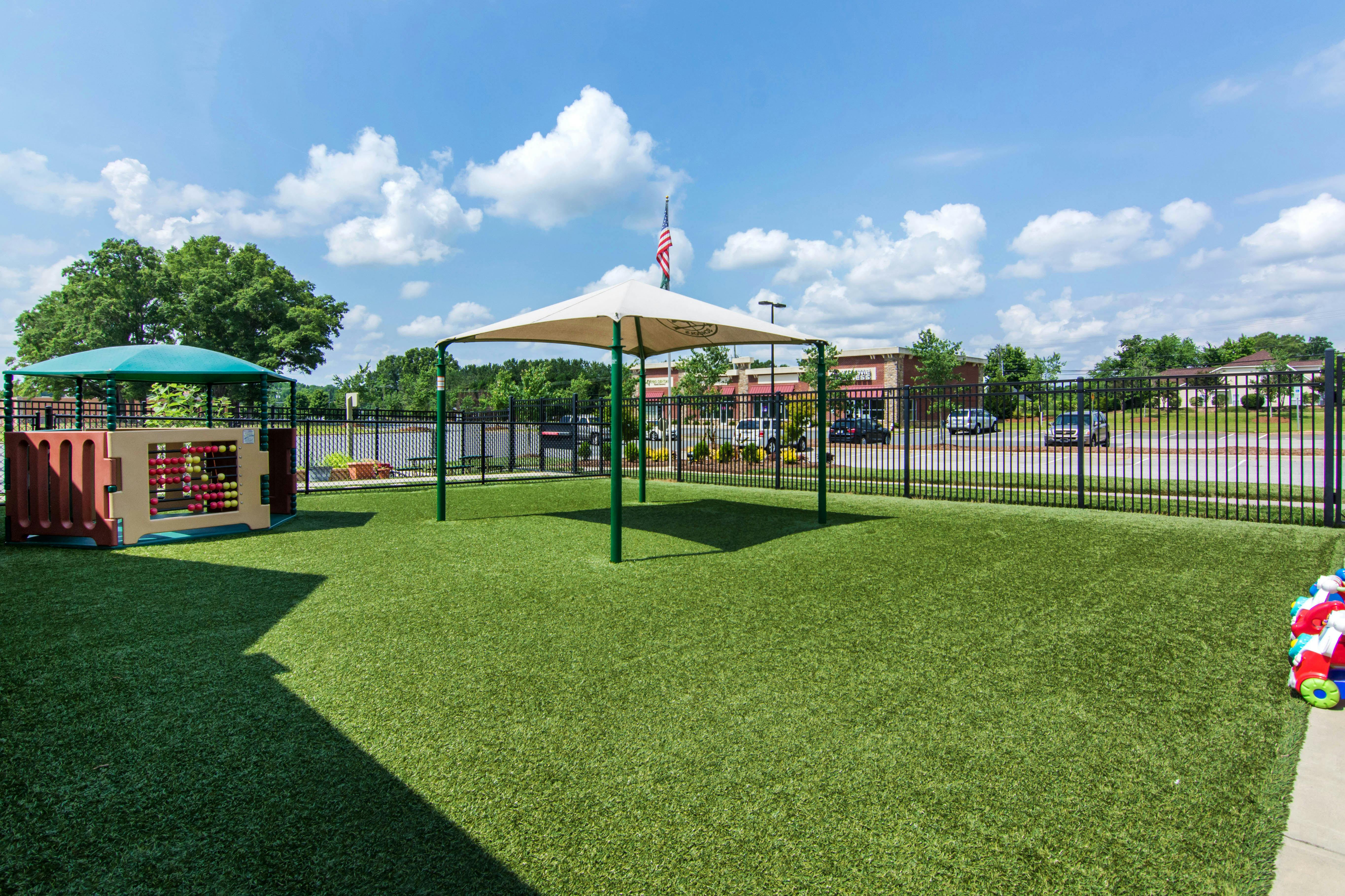 Playground with turf ground, shade structures, and an activity wall