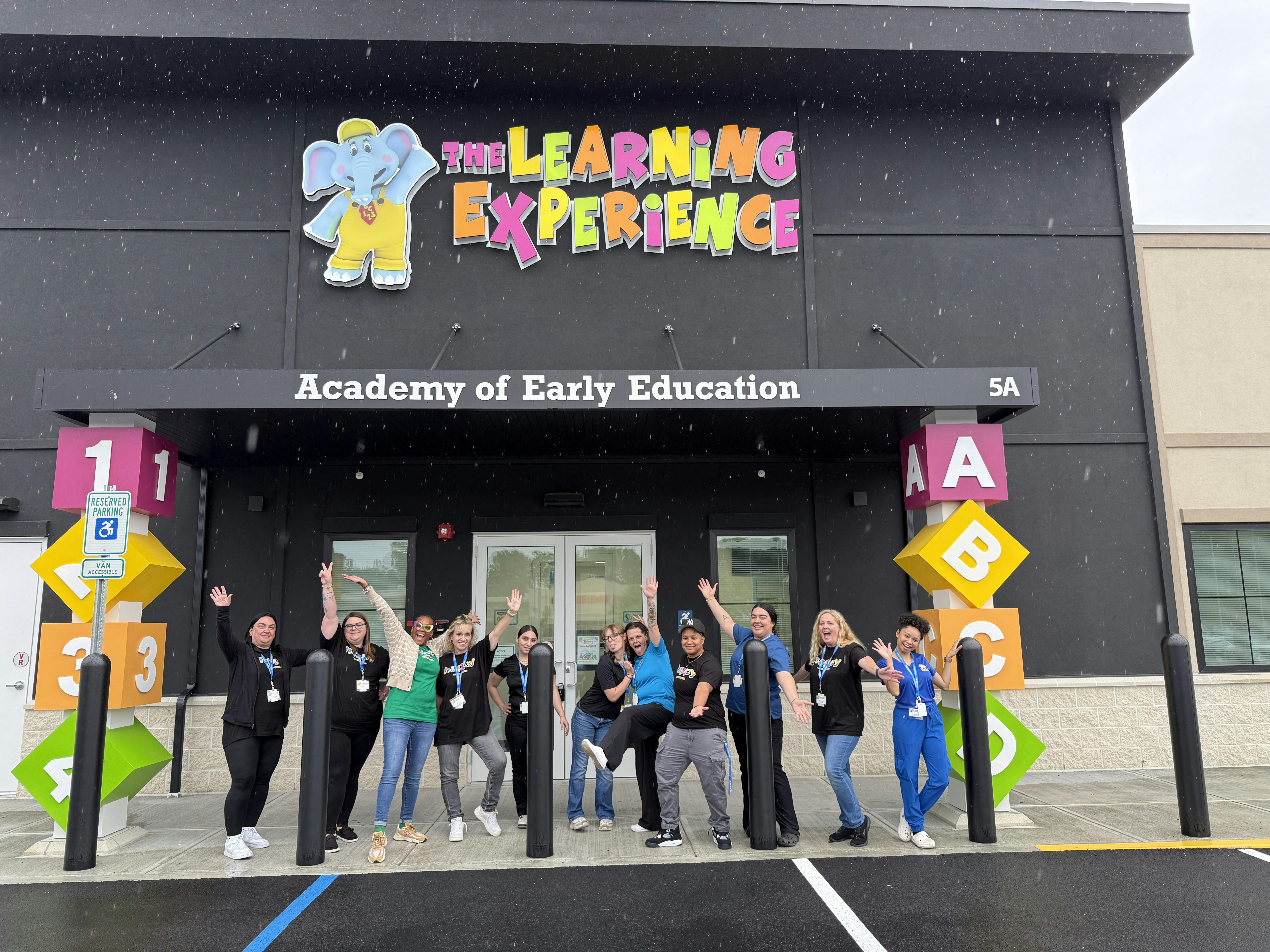 Group of people in front of an "Academy of Early Education" building
