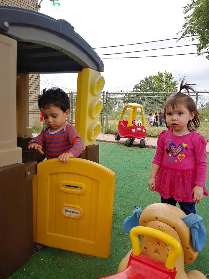 Two children playing on outdoor play equipment