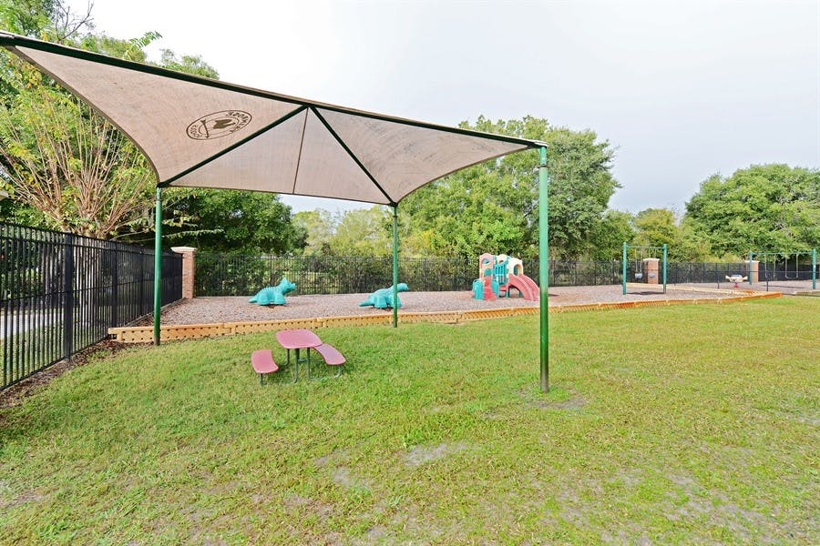 Playground with a large shade structure over sand and play equipment