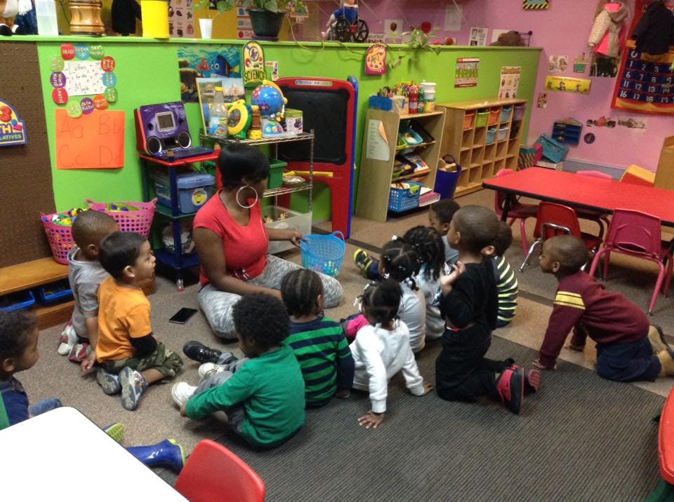 Adult and children sitting on the floor in a classroom