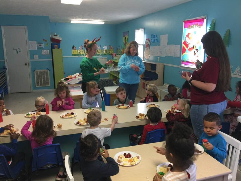 Adults and children gathered around tables with plates of food