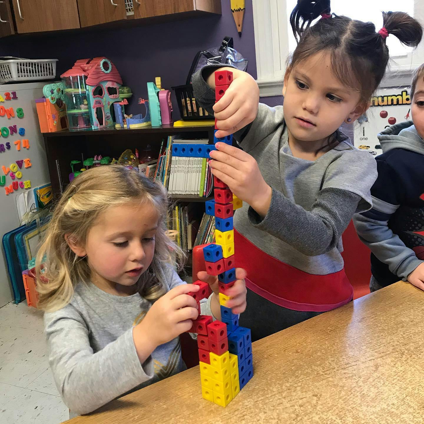 Two children building with colorful interlocking blocks