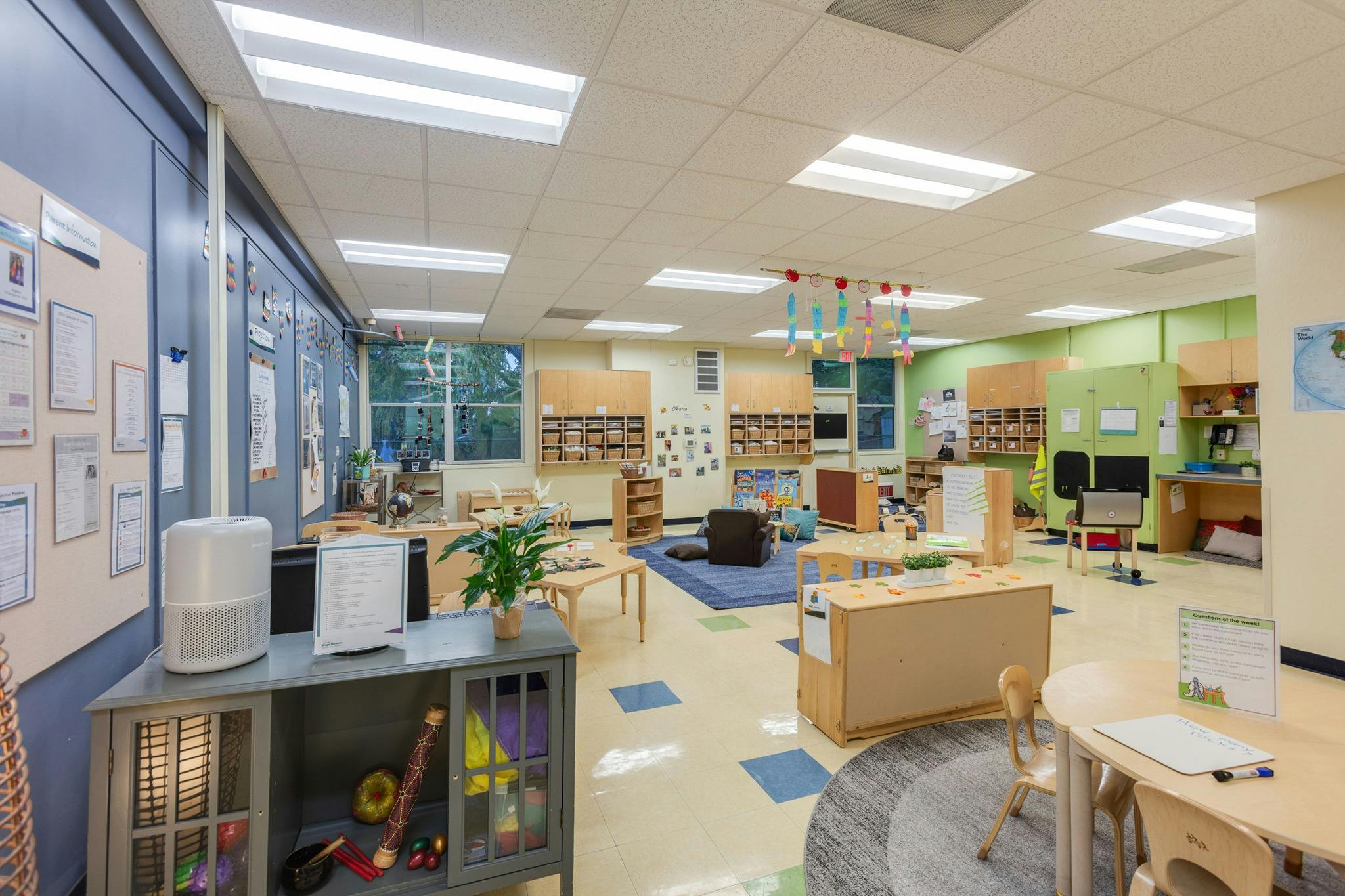 A brightly lit classroom with various learning stations and small tables