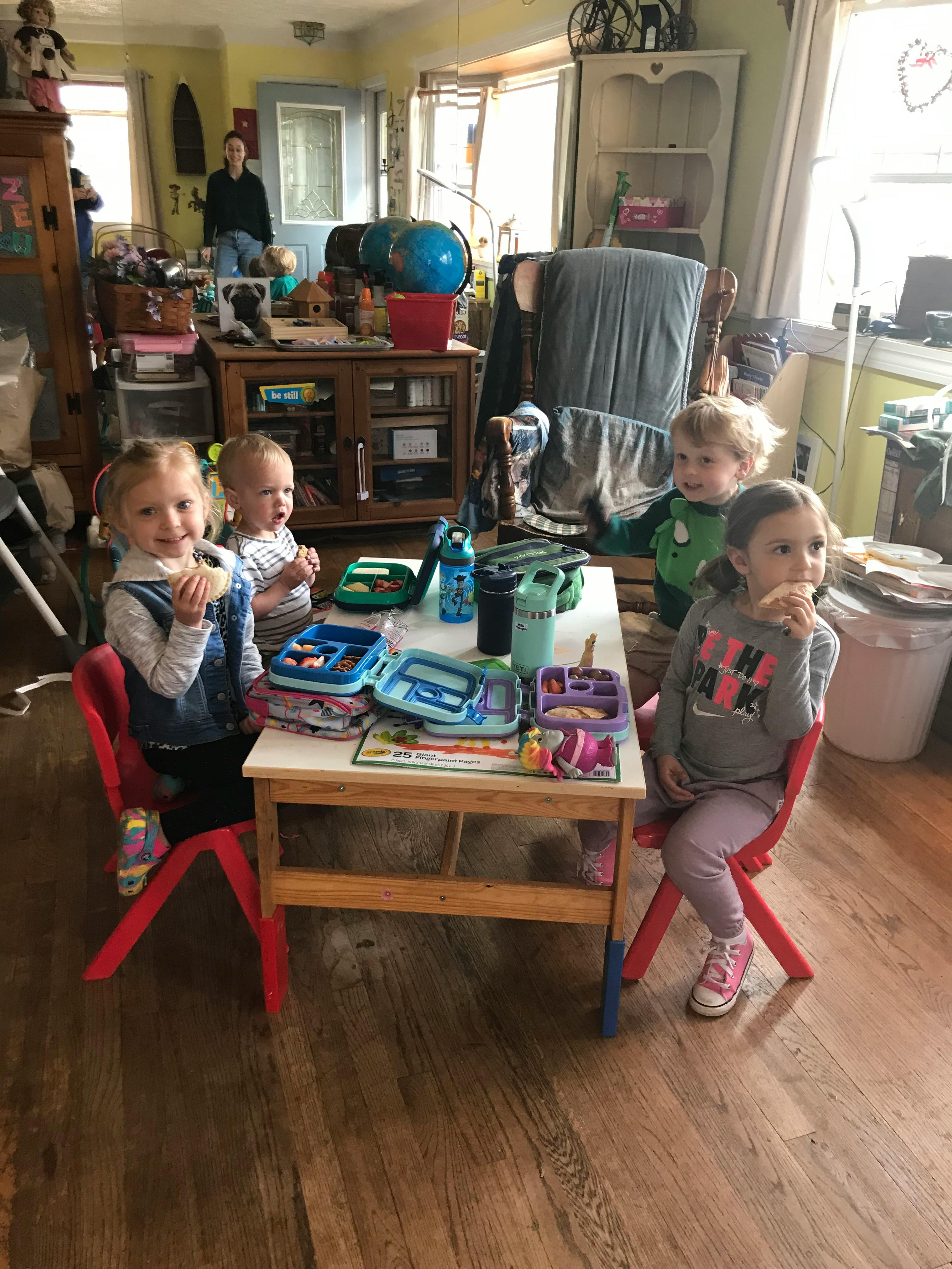 Four children sitting around a small table with open lunchboxes