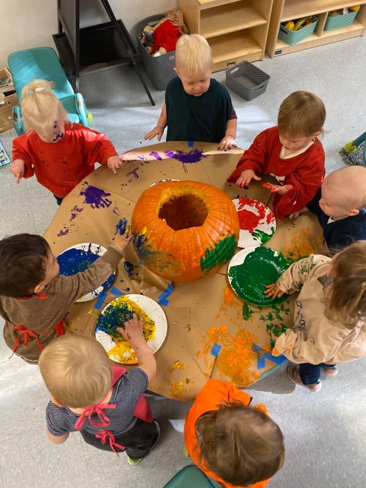 Children painting a pumpkin on a table