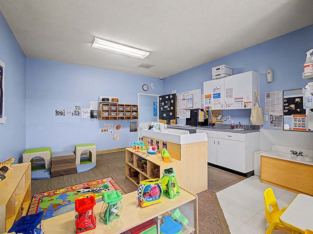 A colorful childcare classroom with toys, playmats, and a changing station