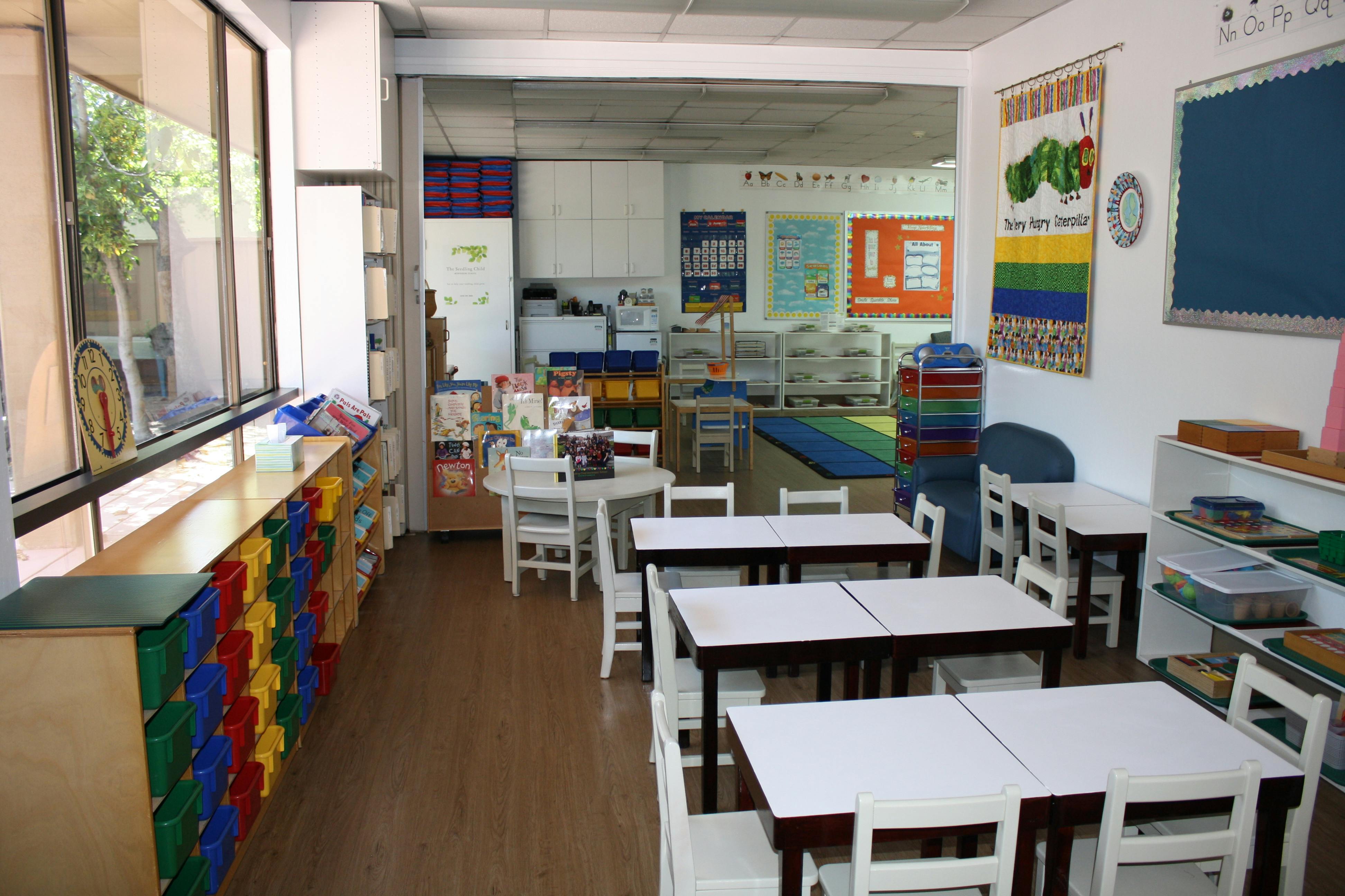 Classroom with small tables and chairs, colorful storage bins, and wall decorations
