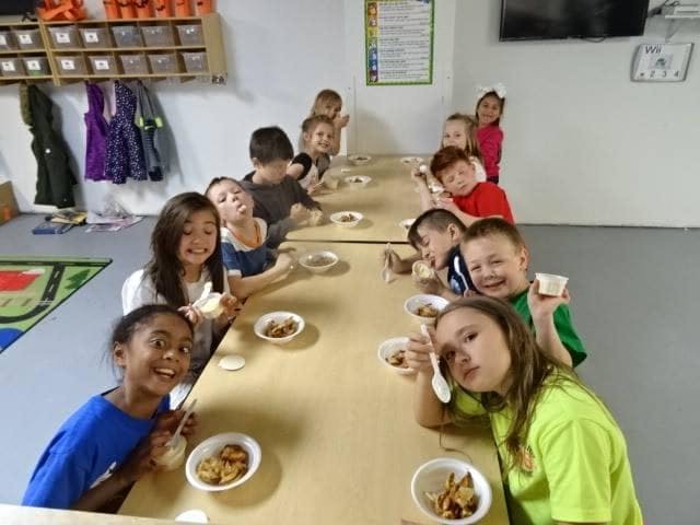 Children sitting at a long table with bowls