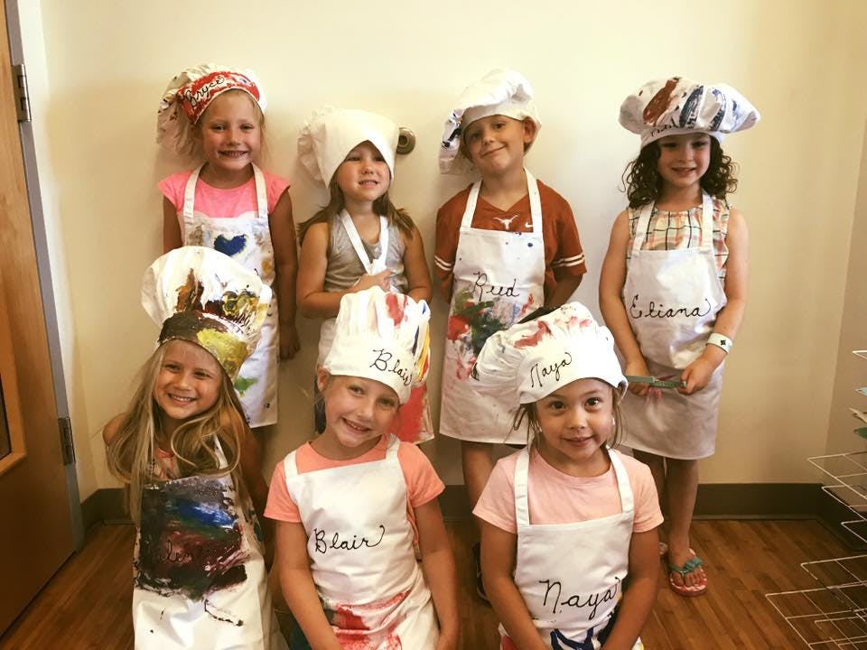 Group of children wearing chef hats and aprons