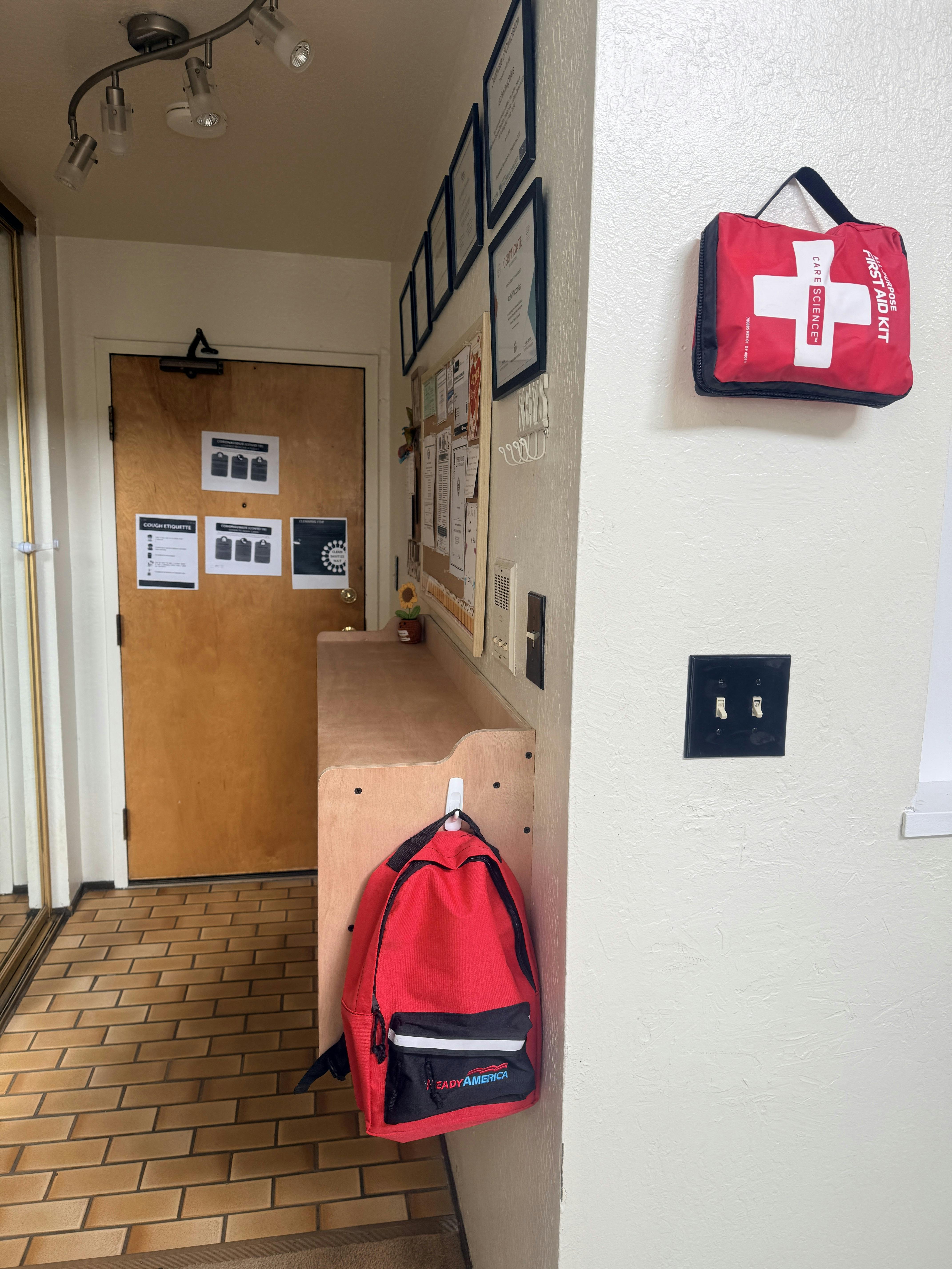 First aid kit on a wall near a backpack hanging on a shelf