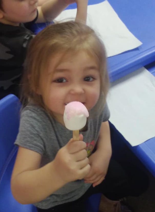 Child eating a treat on a stick