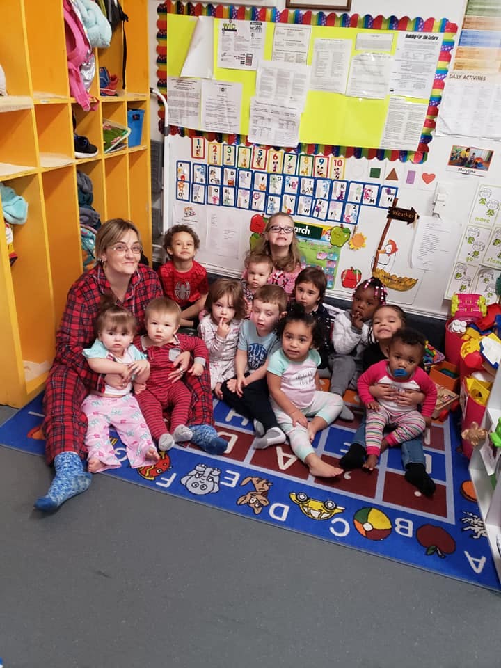 Adult and multiple children sitting on a rug in a classroom