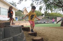 Two children playing on wooden steps in a sandbox