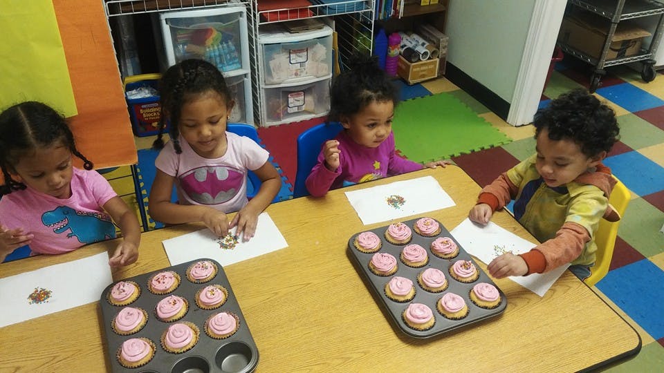 Four children at a table with cupcakes