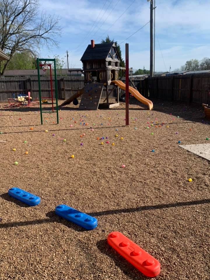 Playground with a wooden playhouse, slide, swings, and colorful balls on the ground