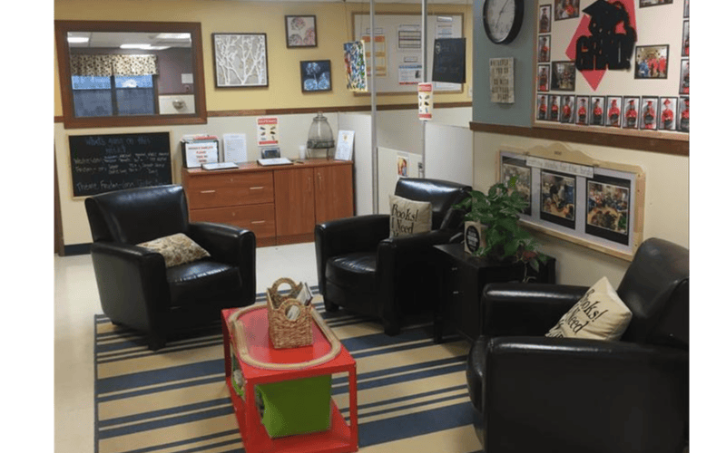 Lounge area with three black leather armchairs and a small red table with a toy train set