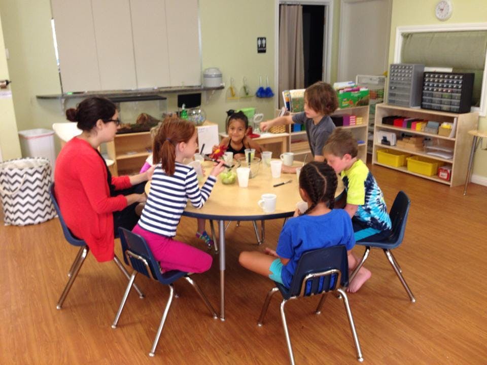 Adult and children sitting around a table in a classroom