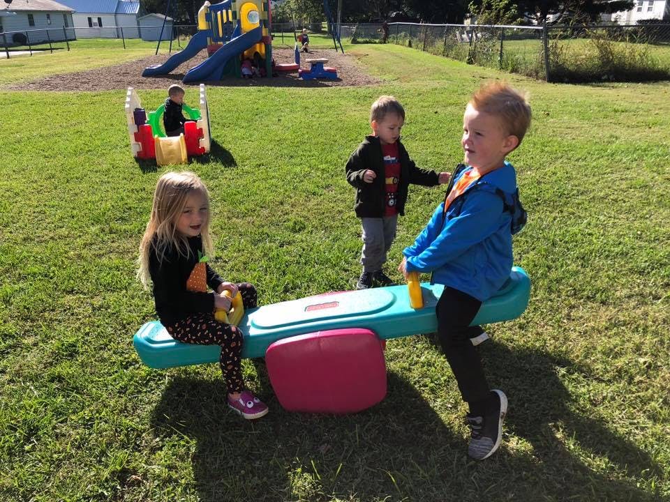 Children playing on a seesaw and other playground equipment