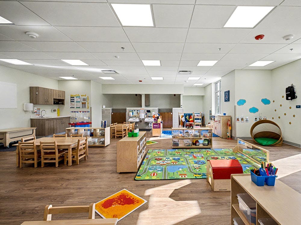 Empty classroom with small tables, chairs, and play areas
