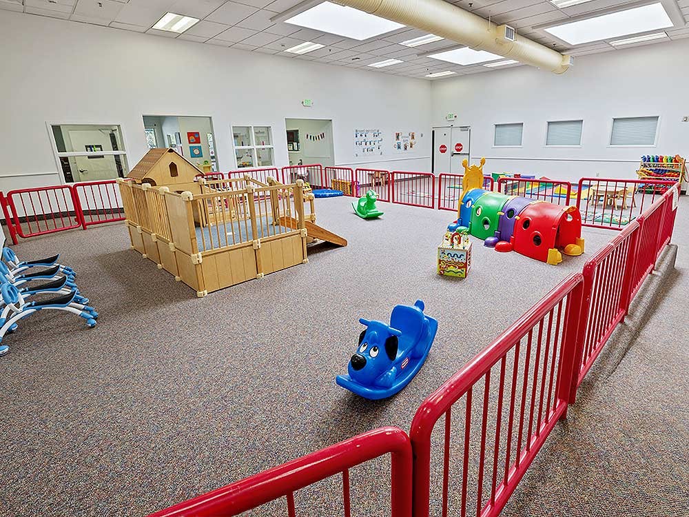 Indoor play area with a wooden playhouse, colorful tunnels, and rocking toys