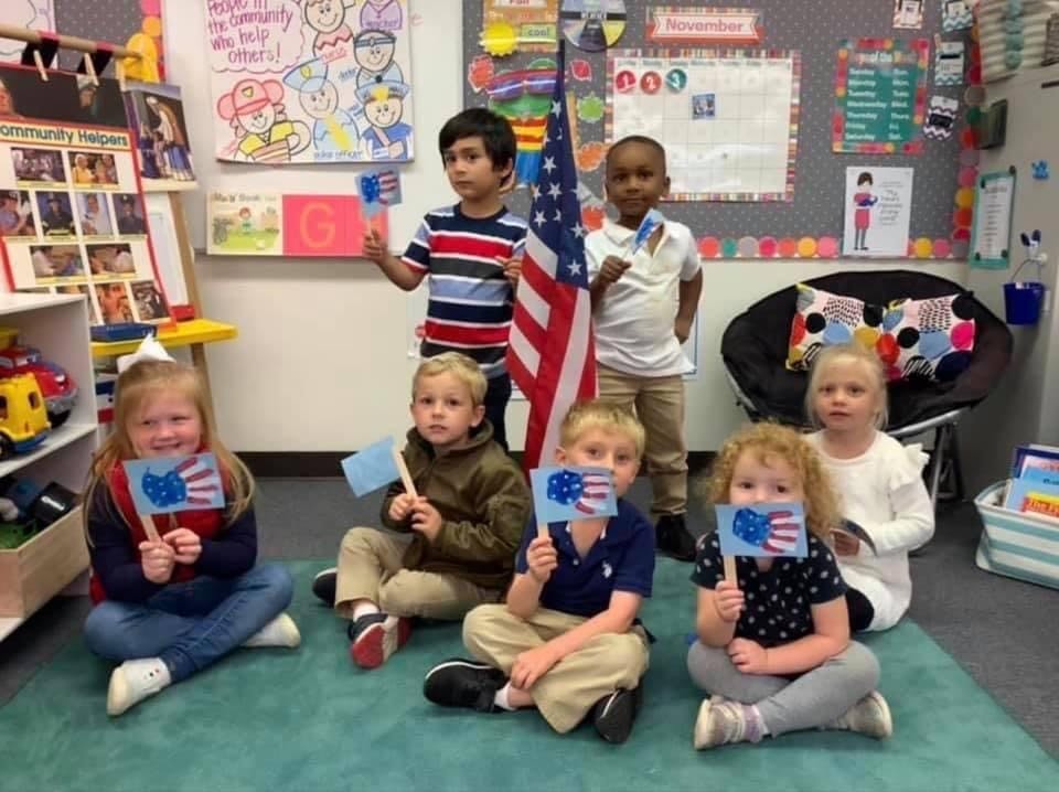 Children holding small American flags in a classroom