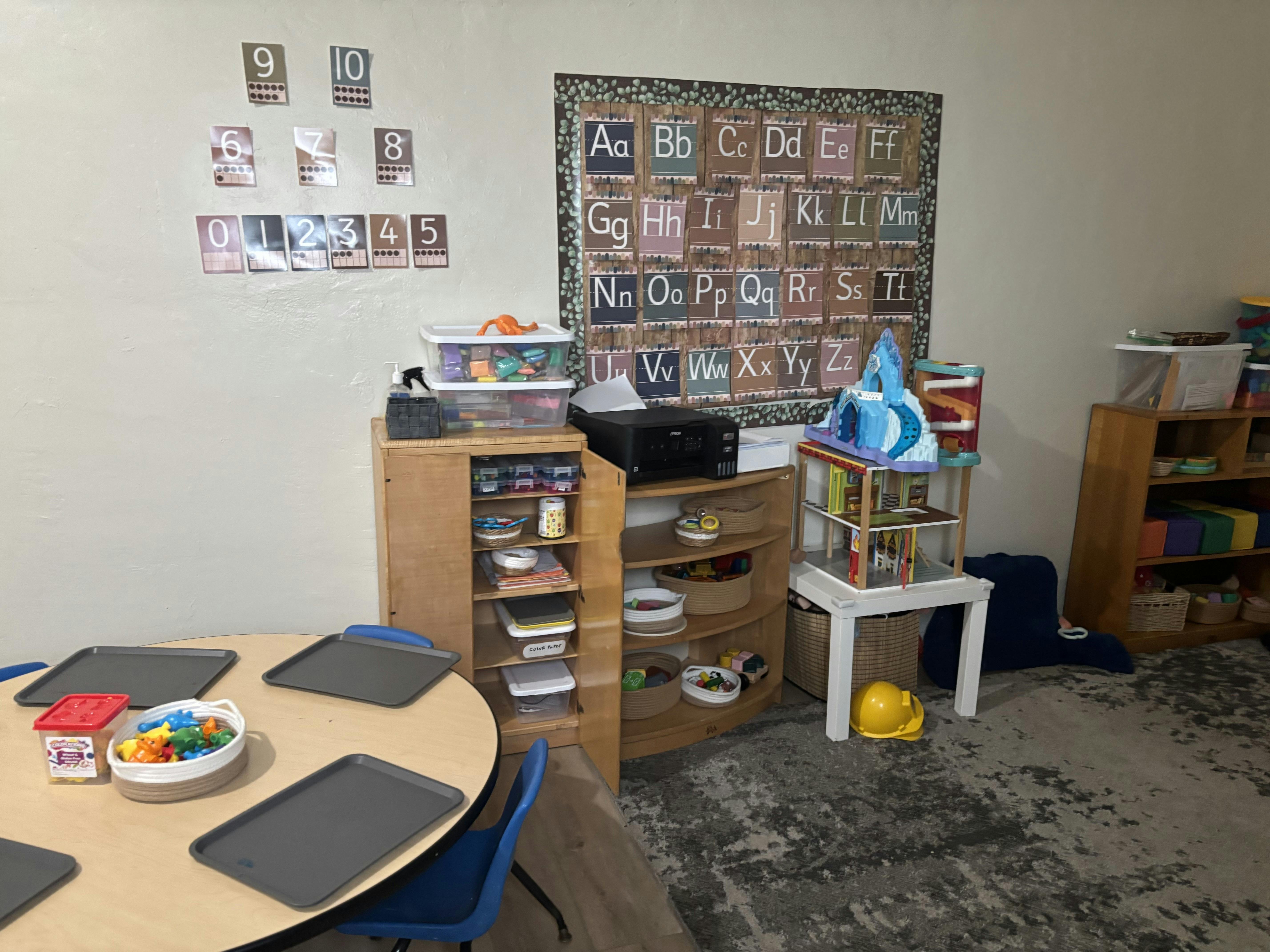Classroom interior with educational wall posters, play equipment, and tables