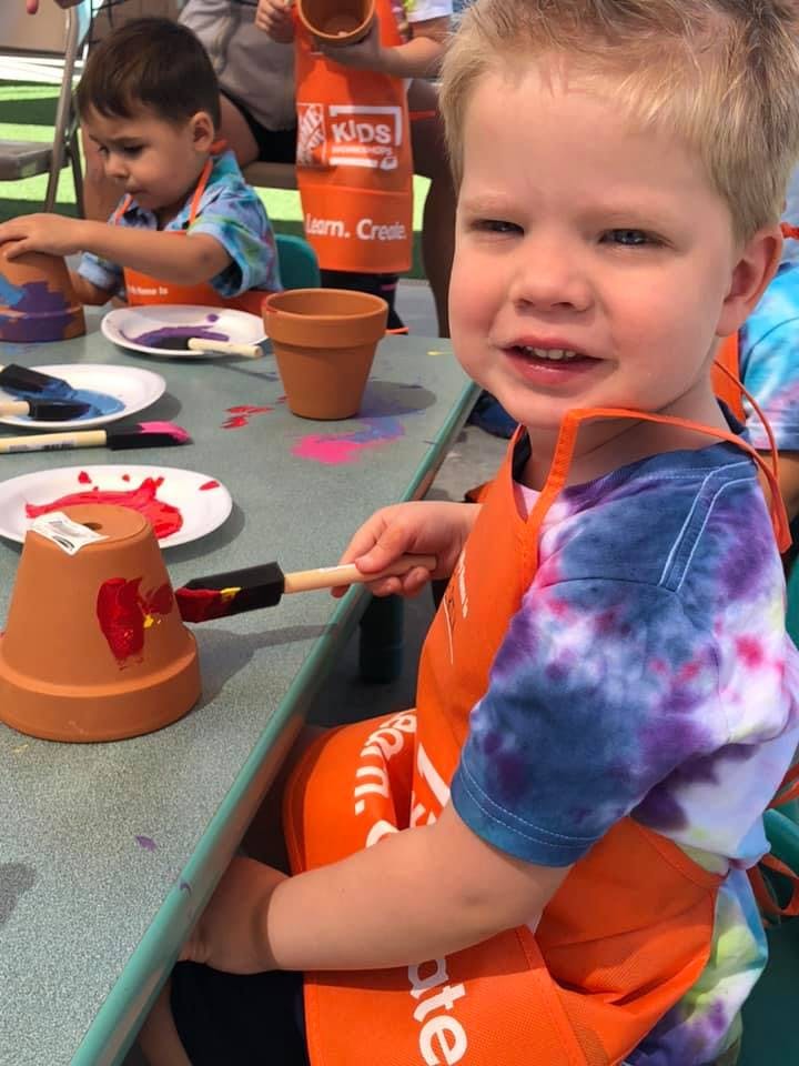 Child painting a terracotta pot at a table