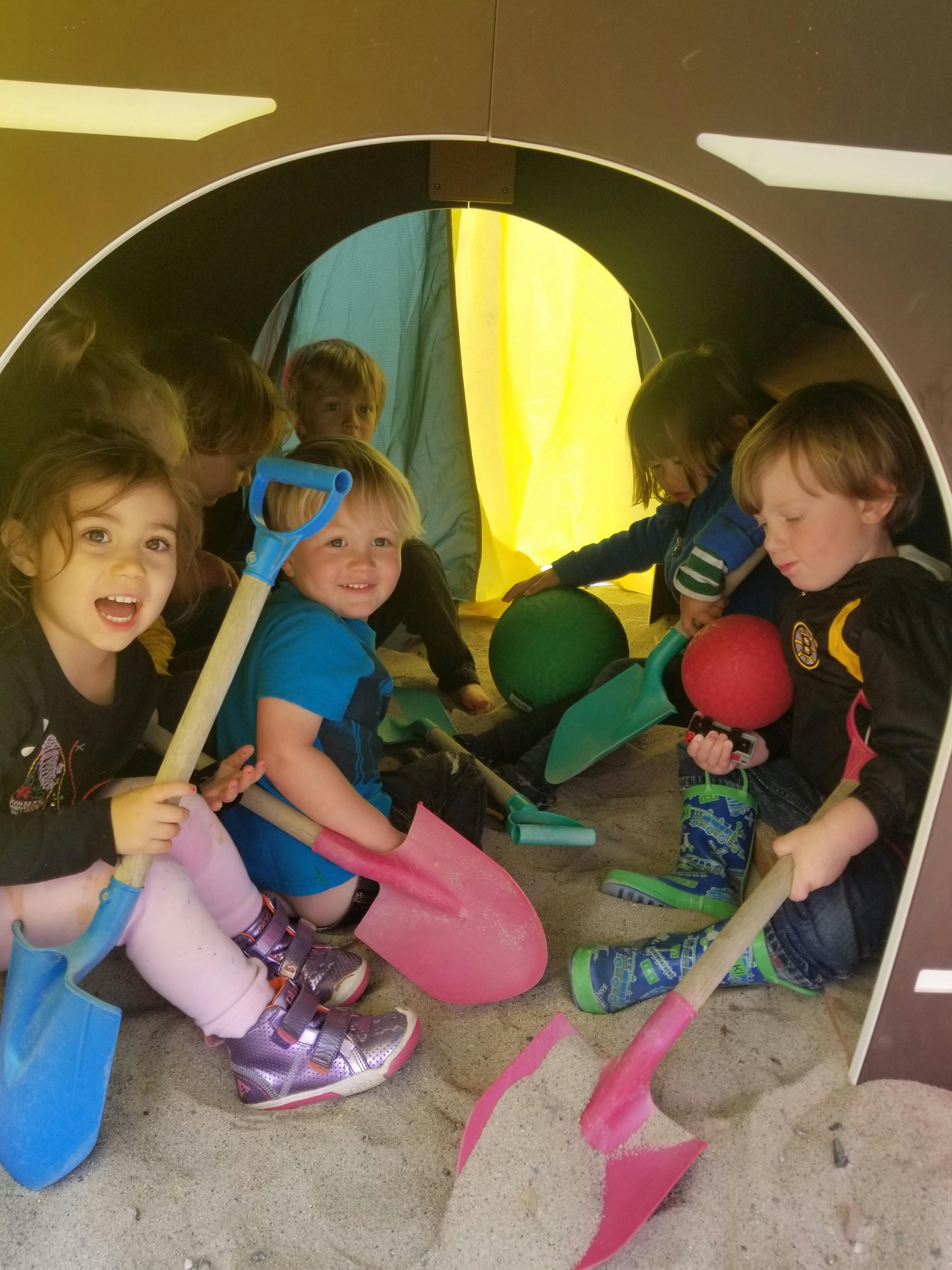 Children playing with shovels and balls in a sandpit