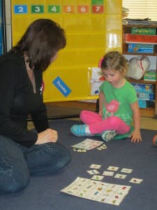 Adult and child on floor playing with cards