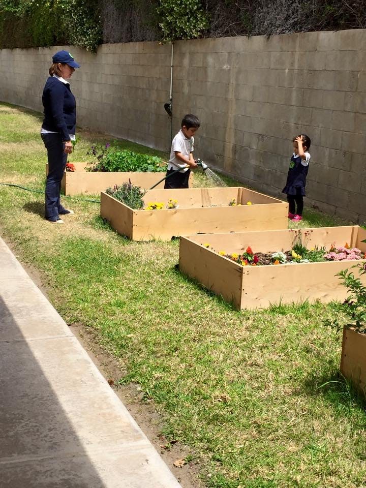 Person and two children watering plants in raised garden beds