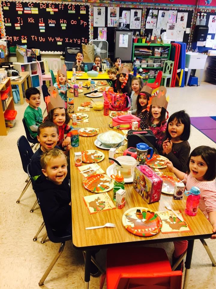 Children sitting at a long table in a classroom