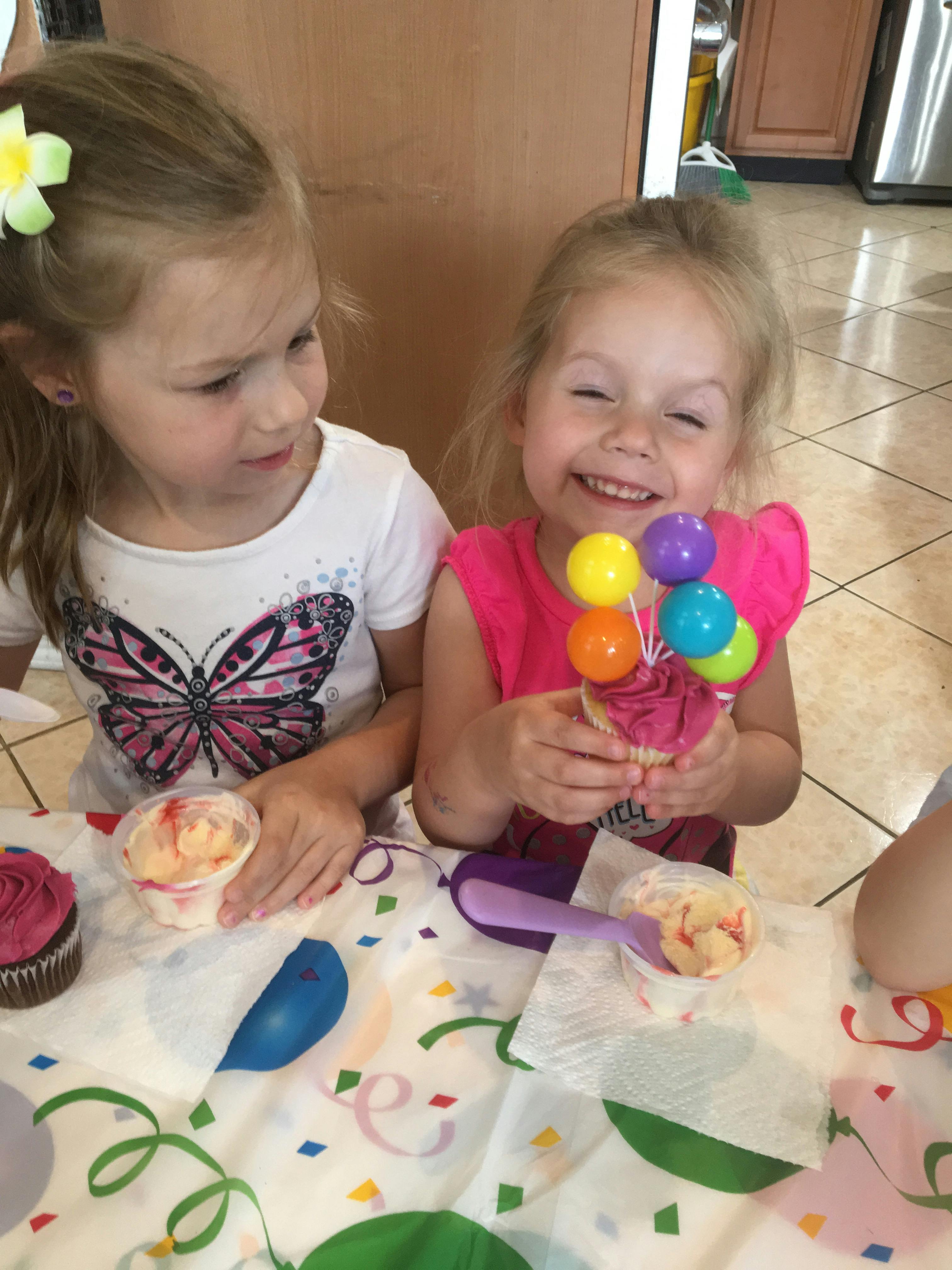 Two children at a table with cupcakes and frosting
