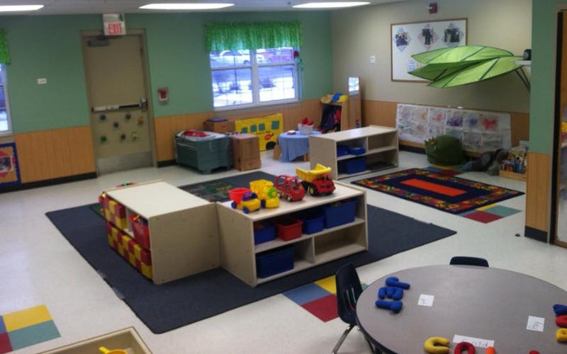 Empty colorful classroom with toys, shelves, rugs, and a table