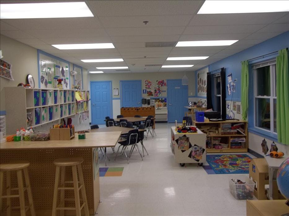 Classroom with tables, chairs, storage shelves, and blue doors
