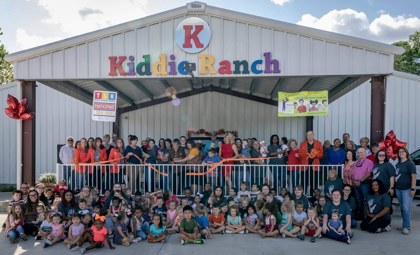 Group of adults and children in front of a building with a sign that says Kiddie Ranch