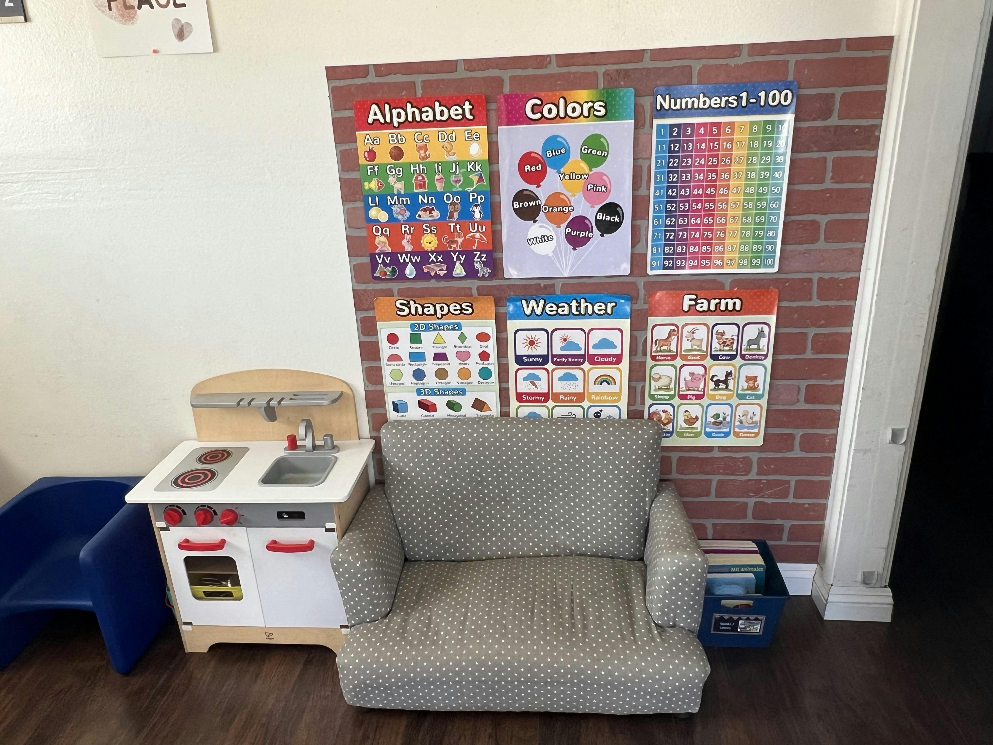 Child-sized sofa and toy kitchen in front of educational wall posters