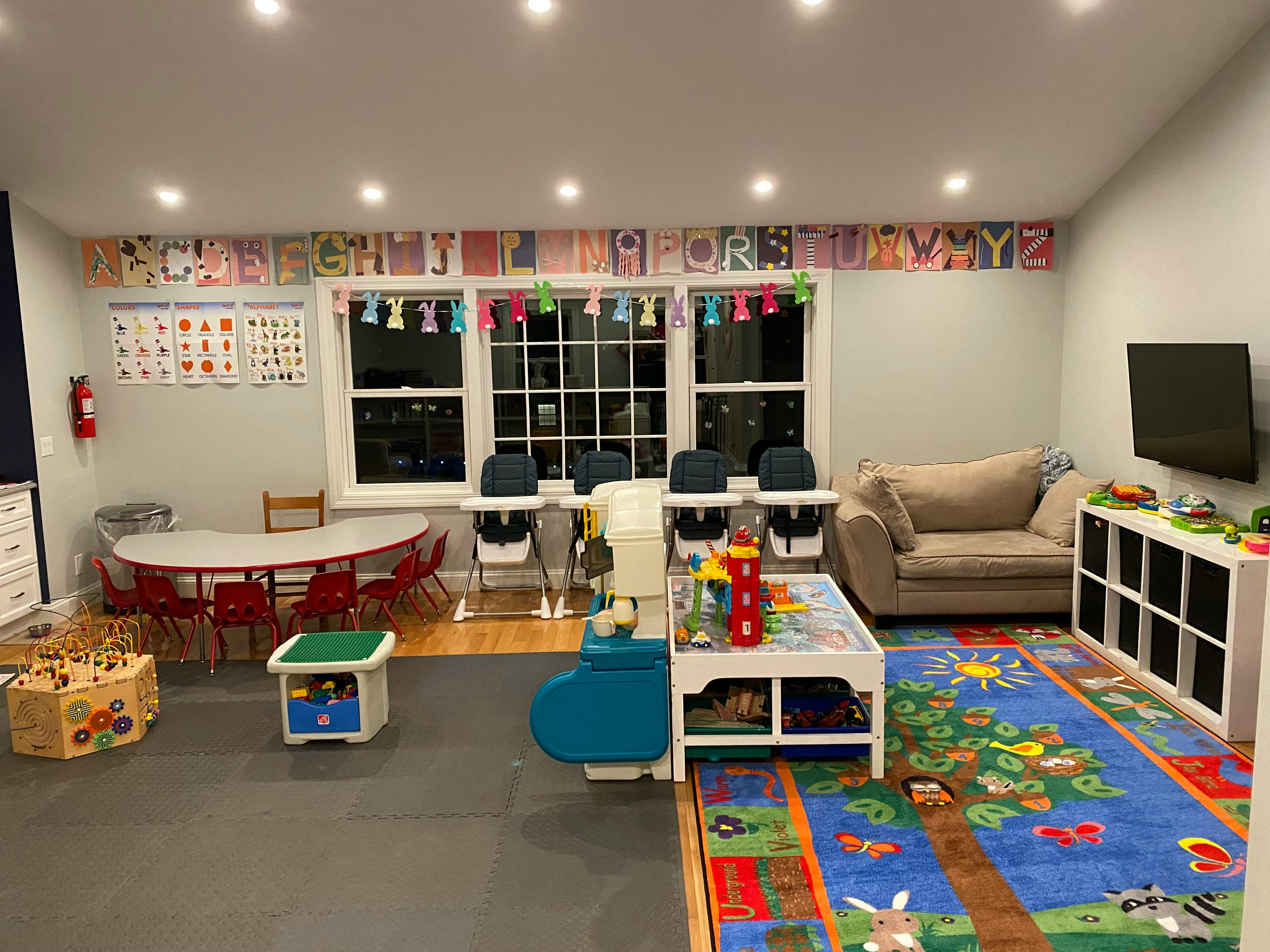 Playroom with tables, chairs, and a colorful rug