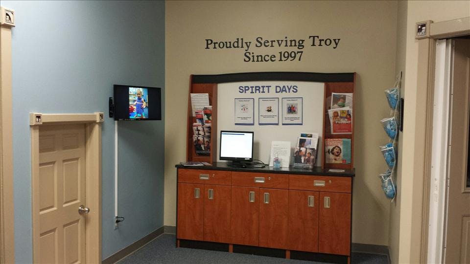 Lobby area with a wooden cabinet, computer, and wall-mounted screen