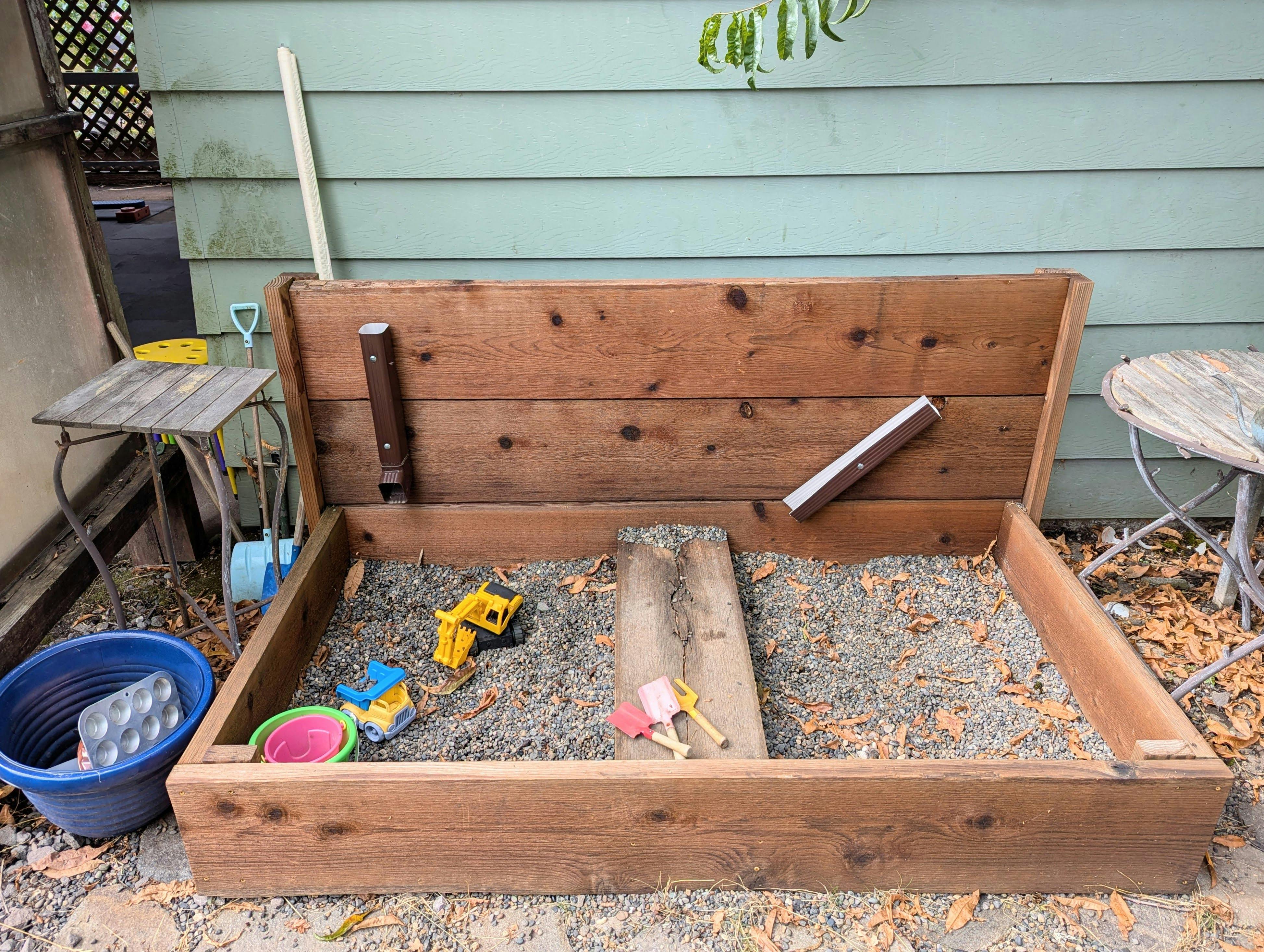 Wooden sandbox with toys and gravel