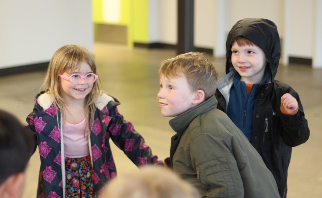 Three children looking at something out of frame subject